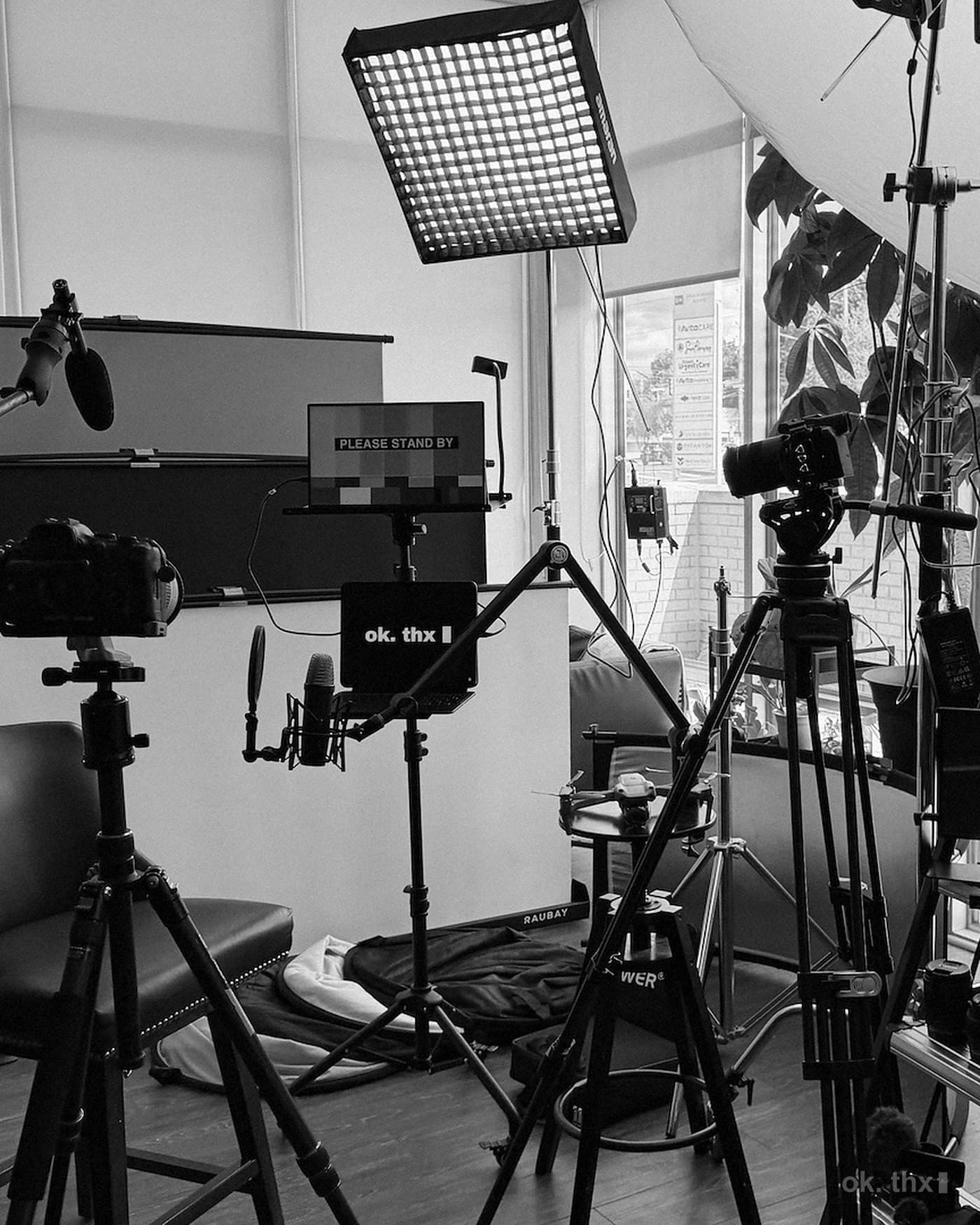 The studio set up for a shoot: LED panel, monitor, boom mic, cameras on tripods and a green screen