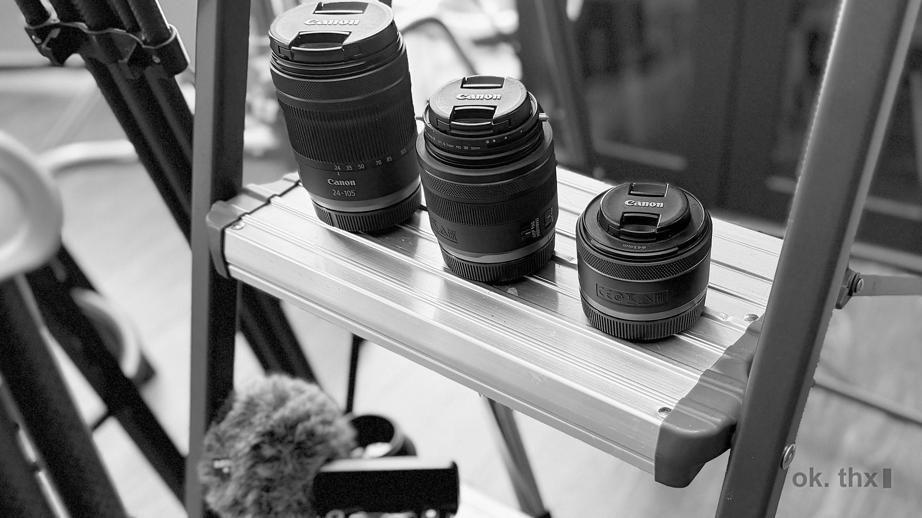 Three lenses and a shotgun microphone on a shelf